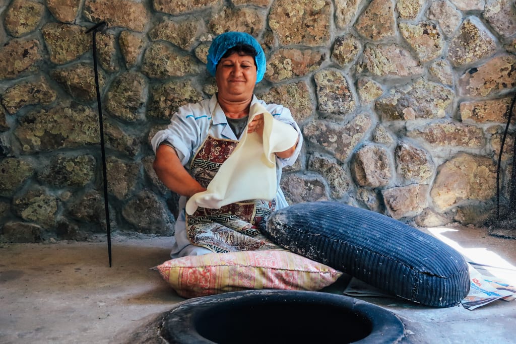 Donna in abiti tradizionali che prepara il pane tipico